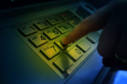 image of a hand on a keypad at a cash machine